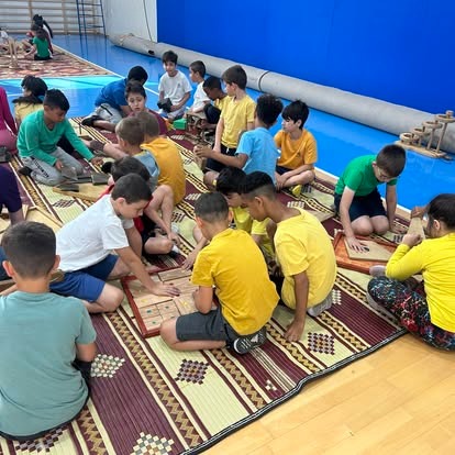 תלמידים יושבים במעגל ומשחקים במשחקי קרשים על מחצלת