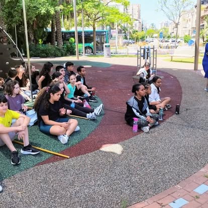 תלמידים יושבים יחד בגינת בית הספר בפעילות חוץ
